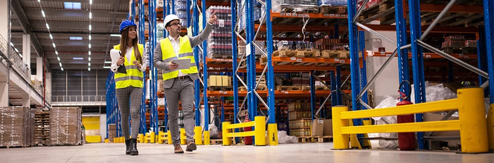 Two warehouse managers walking in a warehouse looking at their inventory